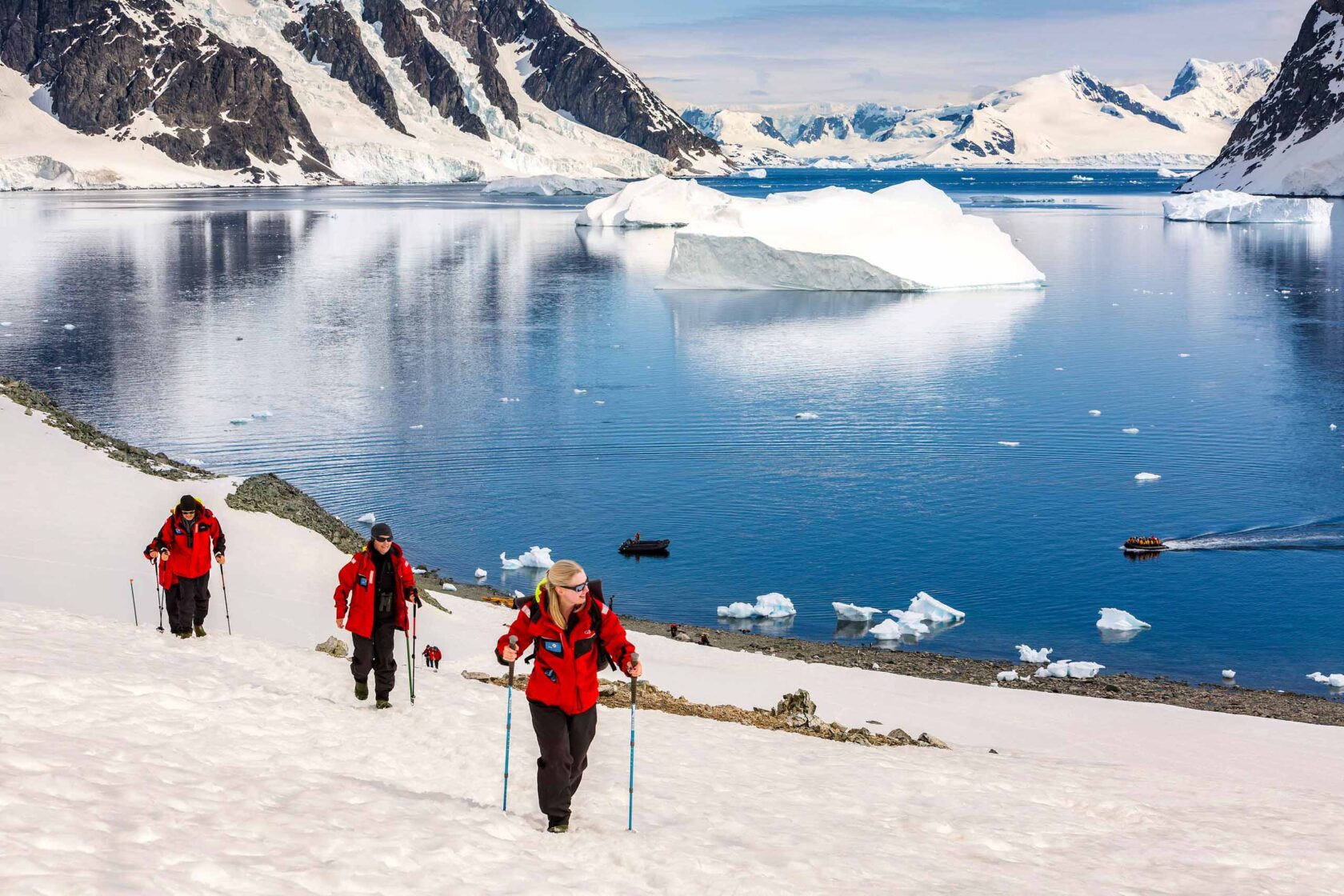 Three people hiking along the Danco Coast in Antarctica.