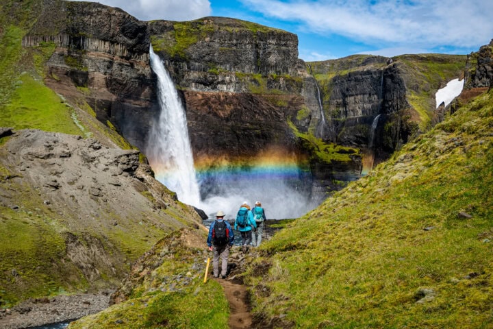 Guided Hiking Group Approaches Háifoss Waterfall in Iceland with Vibrant Rainbow