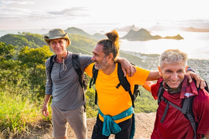 Three Mature Men Hiking Together on a Scenic Mountain Trail at Sunset
