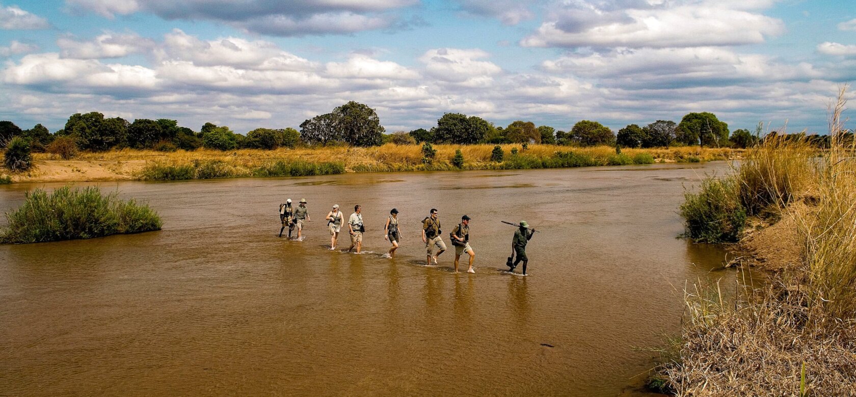 A group of people embarking on an adventure, walking together in a river.